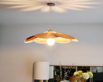 Puede incluir: Una lámpara colgante de tono cobre con un diseño en forma de flor. La lámpara tiene múltiples pétalos que están ligeramente curvados y se superponen entre sí. La lámpara está colgada de un techo blanco y proyecta un brillo cálido.