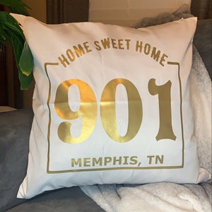May include: White throw pillow with gold text that reads "Home Sweet Home" and "901 Memphis, TN".