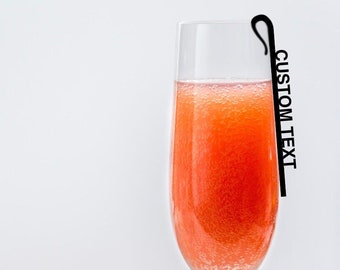 May include: A glass of pink bubbly beverage in a champagne flute with a black metal straw that says "CUSTOM TEXT".