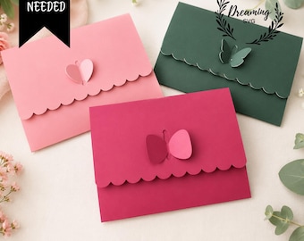 May include: Three paper envelopes in light pink, dark green, and magenta, each featuring a scalloped flap and a butterfly-shaped closure. The text NO GLUE NEEDED is visible in a black banner, and the text Dreaming SVG is in a circular logo.