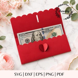 May include: A bright red paper envelope with a scalloped edge flap and a small red heart cutout centred on the front. Inside the envelope, a one hundred dollar bill is visible, featuring the portrait of Benjamin Franklin. The design includes the text Dreaming SVG.