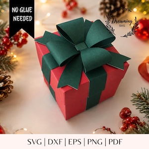 May include: A red square gift box featuring a large dark green paper bow on top. The box is wrapped with dark green paper strips. Text on the image reads NO GLUE NEEDED and Dreaming SVG. The bottom text lists file formats SVG, DXF, EPS, PNG, PDF.