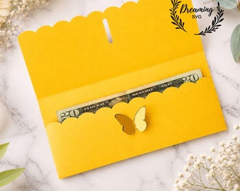 May include: A bright yellow paper envelope with a scalloped edge flap and a central vertical slit. A gold butterfly cutout is attached to the front pocket. A twenty-dollar bill is tucked inside the envelope. The text Dreaming SVG is visible.