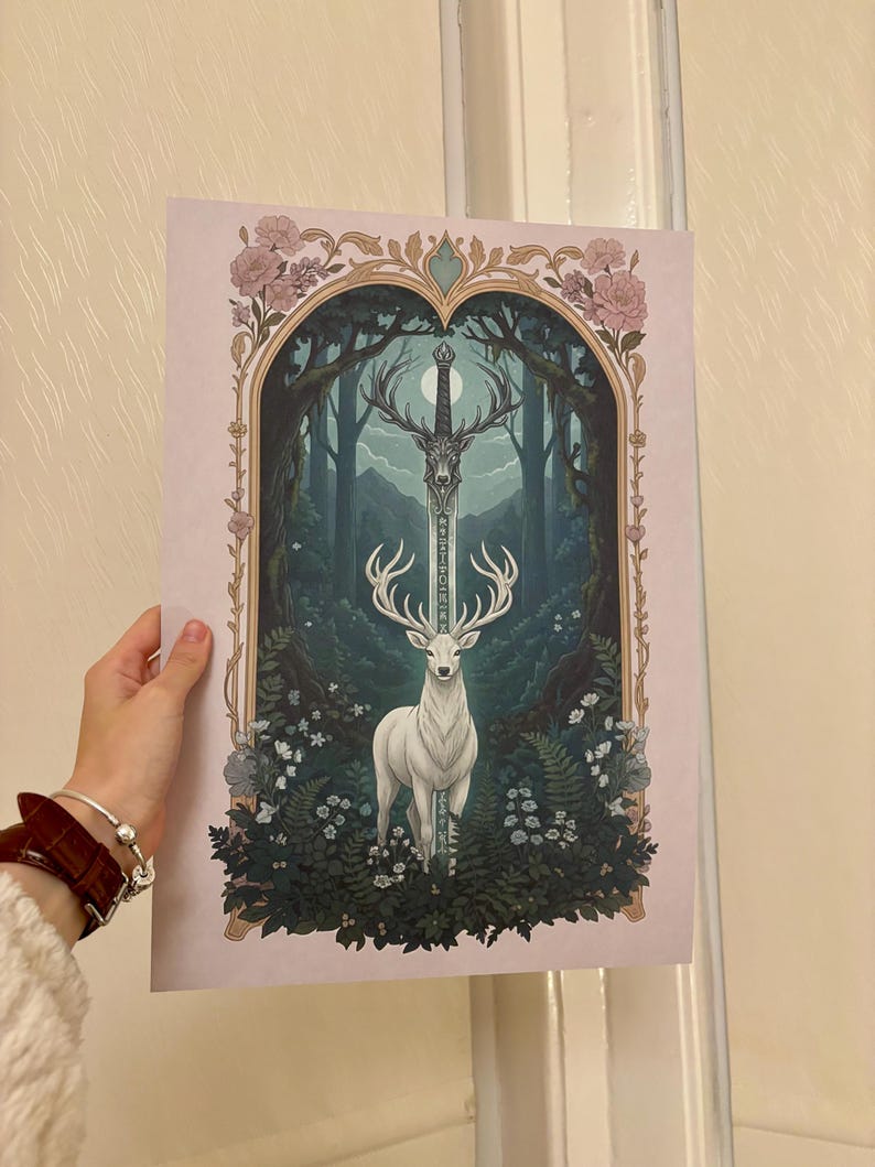 May include: A fantasy art print featuring a white stag with large antlers, standing before a forest scene. A sword is positioned above the stag. The artwork is framed by floral and ornate arch details, with a soft pink background.