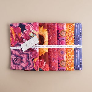 May include: A set of six fabric squares featuring colorful floral and geometric patterns. The fabrics are arranged in a row and tied together with a ribbon. The ribbon has the text "Just keep moving" printed on it.