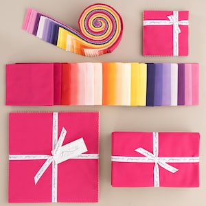 Może przedstawiać: Zestaw 42 kwadratowych kawałków tkaniny w rozmiarze "fat quarter" w tęczy kolorów, w tym różowy, pomarańczowy, żółty, zielony, niebieski, fioletowy i biały. Kwadraty tkaniny są ułożone w stos i zwinięte w rulon. Tkanina jest oznaczona etykietami "Just Keep Sewing" i "True North".