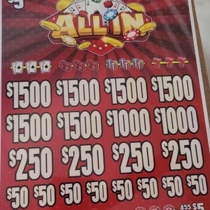 Könnte beinhalten: Ein rotes Rubbellos mit den Worten "ALL IN" in goldenen Buchstaben. Das Los zeigt verschiedene Symbole, darunter Spielkarten, Würfel, Pokerchips und die Zahl 777. Das Los hat auch verschiedene Dollarbeträge aufgedruckt, darunter 1 500 $, 1 000 $, 250 $ und 50 $.