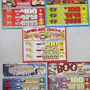 May include: Four lottery tickets with colorful cartoon illustrations. Each ticket has a red, white, and blue theme with the words "All digits in red 100 thru 1500 sign up for chance at seals, five bundles have multiple signers". The tickets are for "Stuff My Stocking", "Turkey Bowl", "Gambling Ghouls", and "Ring in the New Year".