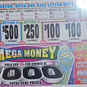 May include: A Mega Money scratch-off ticket with various prize amounts, including $1,000, $500, $250, and $100. The ticket features the text "Mega Money" in a colorful design and lists the number of winners for each prize.