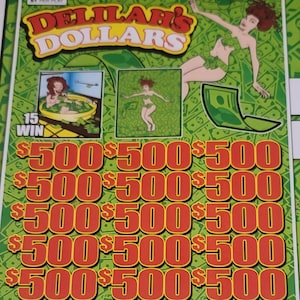 Può includere: Un biglietto gratta e vinci Delilah's Dollars con sfondo verde e giallo. Il biglietto presenta illustrazioni di una donna e il testo "$500" ripetuto più volte. La parte superiore del biglietto recita "$1 PER PLAY".