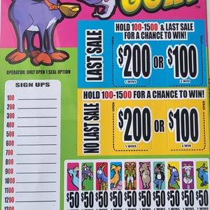 Può includere: Un biglietto di gioco colorato con una capra dei cartoni animati e la scritta "Get Your Goat". Il biglietto presenta premi da 200 €, 100 € e 50 €, con istruzioni per conservare i numeri 100-1500 per avere la possibilità di vincere.