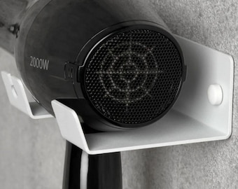 May include: A white wall-mounted hair dryer holder with a black hair dryer. The hair dryer has a black grill and the text "2000W" printed on it.