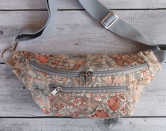 Puede incluir: Una riñonera de color gris con estampado floral, una correa ajustable gris y dos compartimentos con cremallera.
