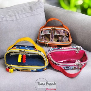 May include: Three colourful zippered pouches with clear plastic windows. The pouches are on a grey sofa. The pouches have different patterns and designs. The text "Tiara Pouch" and "Pattern by Izza Zaya" is visible at the bottom of the image.