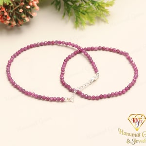 May include: A pink gemstone beaded necklace with a silver clasp. The necklace is made of small, round beads that are strung together on a thin silver chain.