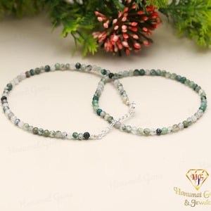 May include: A green and white beaded necklace with a silver clasp. The necklace is made of small, round beads and is approximately 18 inches long.