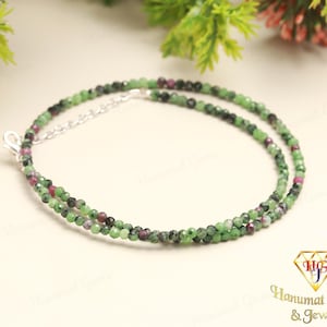 May include: A double strand necklace made of green and pink gemstone beads. The necklace is made of small, round beads and has a silver clasp.