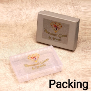 May include: Two jewelry boxes, one gray and one clear, are displayed. The gray box has a label with a logo and the text "Hanumat Gems & Jewels." The clear box is open, and the word "Packing" is written in black at the bottom.