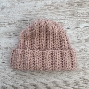 May include: A pink crocheted beanie hat with a ribbed texture.