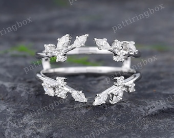 May include: A delicate silver ring with a split design featuring two branches of leaves with small diamonds. The ring is designed to be worn on two fingers.