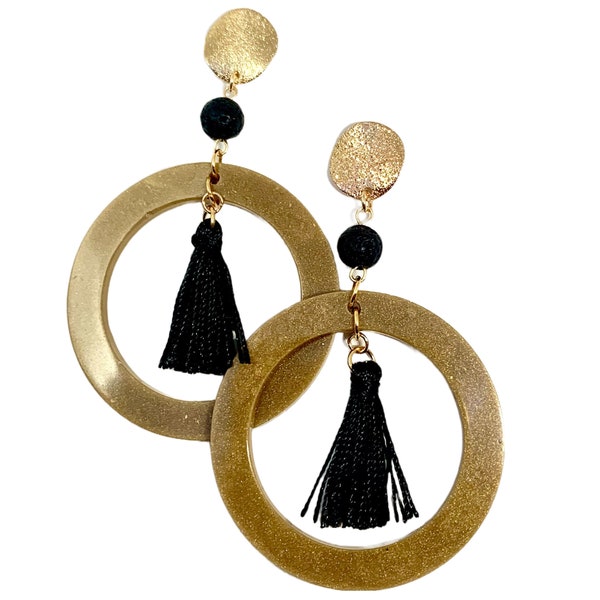 Boucles d'oreilles longues esprit zen japonais - Anneaux en résine aspect métal or vieilli, avec perles de lave et pompons noirs dansants.