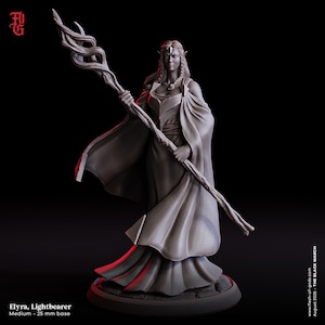 May include: A grey resin miniature figure of a standing elf character named Elyra, Lightbearer. The figure wears a long flowing robe and holds a tall, twisted wooden staff. It is mounted on a circular 25 mm base against a black background.