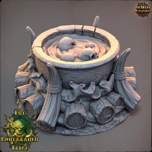 May include: A grey miniature cauldron with skulls in liquid, set on logs and brooms. The cauldron is surrounded by decorative elements. The text "The Boneranch Tribe" is visible.