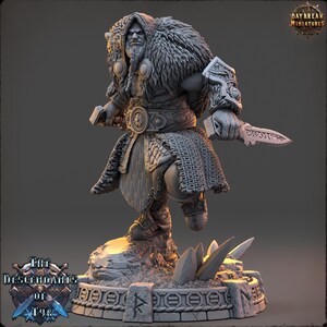 Puede incluir: Figura en miniatura detallada de un guerrero, vestido con pieles y armadura, sosteniendo un cuchillo. La figura se encuentra sobre una base rocosa con el texto "The Descendants of Tyr" y "Daybreak Miniatures".