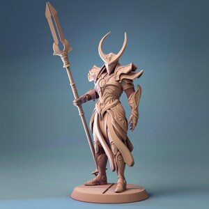 May include: A beige figurine of a warrior in detailed armour, holding a spear. The warrior wears a horned helmet and stands on a circular base. The armour has intricate details and a flowing skirt-like design.