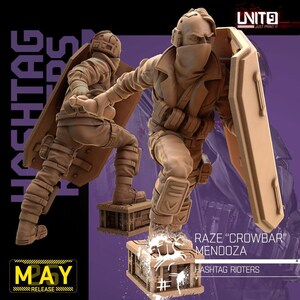 May include: A tan-colored miniature figurine of a tactical character named Raze Crowbar Mendoza, part of the Hashtag Rioters collection. The figure wears a face mask, tactical gear, and carries a large rectangular shield while standing on a crate.