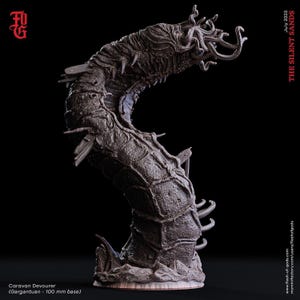 May include: A dark grey, segmented, worm-like creature figurine with a textured, armoured body, multiple curved appendages, and a cluster of tentacles at the head. The base is labelled 100 mm, and text reads Caravan Devourer and THE SILENT SANDS.