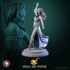 May include: A detailed, gray figurine of a woman in a flowing gown, with her arm raised. She wears a floral crown and armbands. The base reads "GRACE AND POWER" with a flaming bowl graphic. A second, larger statue is in the background.