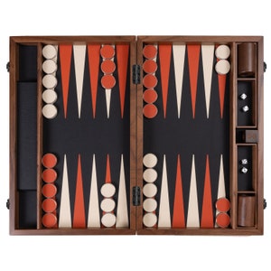 May include: A wooden backgammon set with a black playing surface, featuring orange, white, and black triangular points. The set includes wooden game pieces, dice, and dice cups. The set is open, ready for play.