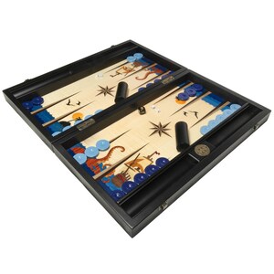 May include: A wooden backgammon game set with a nautical theme. The board is open and shows the playing surface with blue and white chips, dice, and a compass design. The board is made of wood and has a black finish.