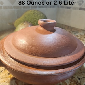 May include: A terracotta cooking pot with a lid. The pot is 5 inches tall and 11 inches wide. It has a capacity of 88 ounces or 2.6 liters.