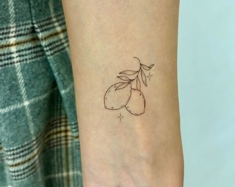 May include: A simple line drawing tattoo of two lemons on a branch with small stars.