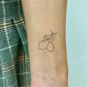 May include: A simple line drawing tattoo of two lemons on a branch with small stars.