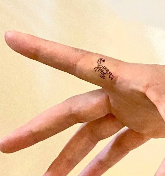 Fine line scorpion tattoo on the finger