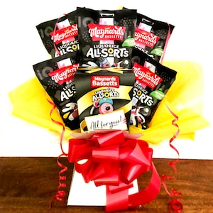 May include: A yellow gift box filled with black bags of Maynard's Liquorice Allsorts sweets. The box is tied with a red ribbon and has a small card that says "All for you!"