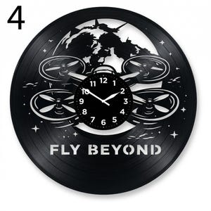 May include: Black vinyl record clock with a drone design and the words "FLY BEYOND". The clock face is black with white hands and numbers. The design includes a world map and stars.