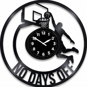May include: Black basketball-themed wall clock. The clock features a silhouette of a basketball player dunking, a hoop, and a basketball. The clock face is black with white numbers and hands. The words "NO DAYS OFF" are cut out at the bottom.