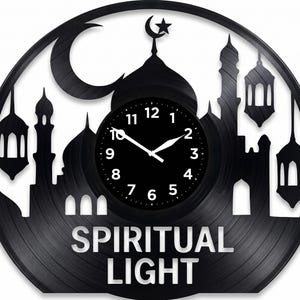 May include: Black wall clock with a mosque silhouette design, a crescent moon, and star. The clock face is black with white hands and numbers. The words "SPIRITUAL LIGHT" are displayed at the bottom. A unique decorative piece.
