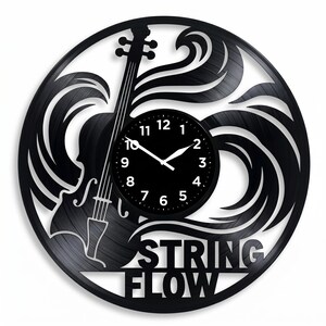 May include: Black wall clock with a violin silhouette and the words "STRING FLOW" cut out of a vinyl record. The clock face is black with white numbers and hands. The design includes flowing lines around the violin.
