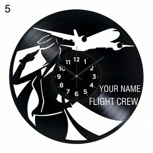 May include: Black vinyl record clock with a white silhouette of a pilot and a passenger jet. The clock face is black with white numbers and hands. Text reads "YOUR NAME FLIGHT CREW".