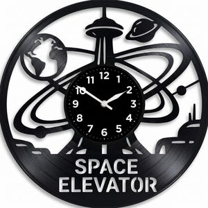 May include: Black wall clock with a space theme, cut from a vinyl record. The clock features a planet Earth, a Saturn-like planet, and a tower. The words "SPACE ELEVATOR" are at the bottom. The clock hands show the time.