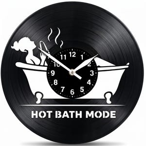 May include: Black vinyl record clock with a white silhouette of a person relaxing in a bathtub. The clock face is black with white numbers and hands. The text "HOT BATH MODE" is printed at the bottom.