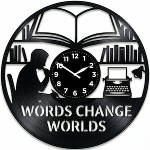 May include: Black vinyl record clock with a literary theme. The clock features a silhouette of a person reading, a typewriter, and the words "WORDS CHANGE WORLDS." The clock hands point to 2:50. Bookshelves and an open book are also depicted.