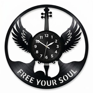 May include: Black vinyl record wall clock with a violin-shaped design, wings, and the words "FREE YOUR SOUL." The clock face has white numbers and hands. The clock is approximately 12 inches in diameter.