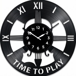 May include: Black wall clock made from a vinyl record. The clock face is black with white numerals and hands. The outer ring has Roman numerals and the words "TIME TO PLAY".