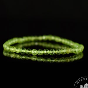 Op de afbeelding: Een groene edelsteen armband gemaakt met gefacetteerde kralen. De armband ligt op een zwarte achtergrond.